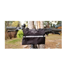 Load image into Gallery viewer, Little roller bike bag with reflective stripe shown on bike handlebars in a forest setting
